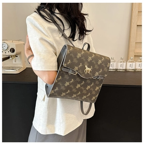 Détail d'un sac à dos en cuir marron foncé avec imprimé calèche et boucle de cheval en métal