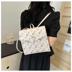 Détail d'un sac à dos beige avec motifs de calèche et boucle dorée en forme de cheval