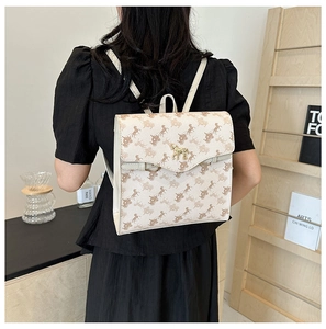 Gros plan du sac à dos beige avec imprimé carrosse et boucle dorée en forme de cheval