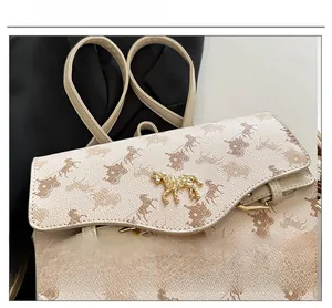 Détail du fermoir carrosse doré sur cuir beige avec motifs de chevaux imprimés