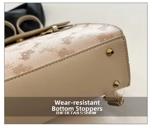 Détail du dessous de sac avec pieds en métal doré et imprimé monogramme sur cuir