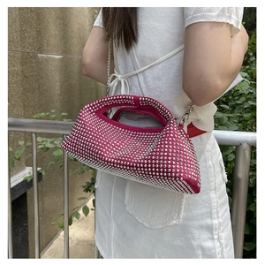 Outdoor shot of a rose red rhinestone crossbody bag with silver chain strap and top handle