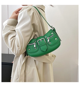Detail of bright green baguette bag with silver rivets and zippers on beige coat