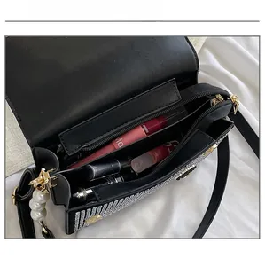 Detail view of the black rhinestone bag interior with main compartment and zipper pocket