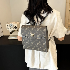 Sac à dos gris vintage avec motif calèche et ornements de cheval dorés dans un café