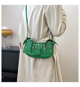 Detail of green punk shoulder bag with silver studs and buckles on beige trench coat