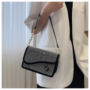 Close-up of sparkling rhinestone shoulder bag with black bear ornament and pearl strap