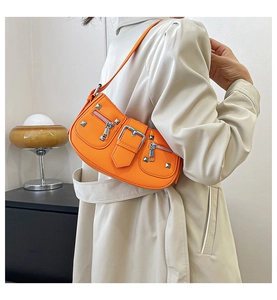 Detail view of orange leather shoulder bag featuring silver rivets and metal buckle closure
