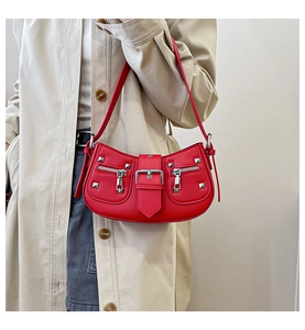 Detail of red crescent motorcycle bag with silver rivets and zippers on a trench coat model