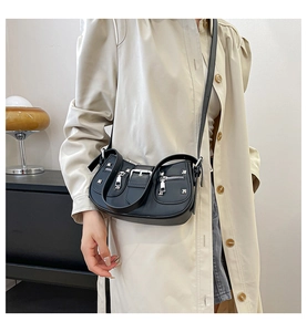 Close-up of black rivet shoulder bag with silver hardware and belt buckle detail