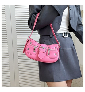Close-up of pink rivet baguette bag with silver studs and buckle worn by model