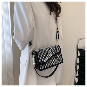Detail of a black rhinestone crossbody bag with flower clasp and pearl charm detail