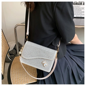 Detail of white rhinestone shoulder bag with pearl chain and bear ornament