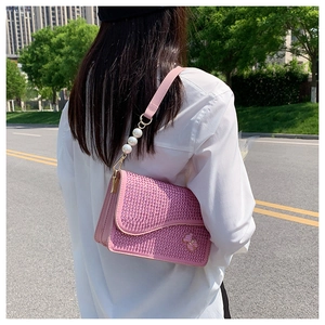 Pink rhinestone handbag detail featuring a pearl chain strap and a small bear ornament