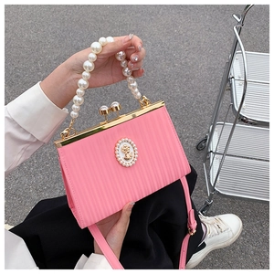 Macro view of pink vintage clutch featuring pleated texture and pearl emblem decoration