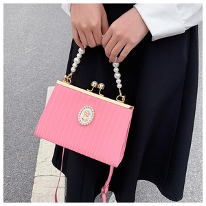 Detail of pink textured evening bag featuring pearl handle and vintage portrait emblem