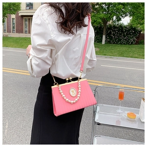 Pink evening bag with pearl handle and vintage badge, styled on model in street scene