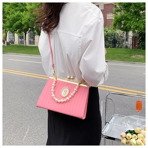 Detail of pink vintage crossbody bag with pearl handle and retro relief decoration