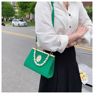 Detail of green retro handbag with pearl handle and golden vintage badge emblem