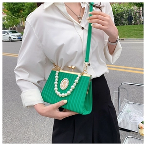 Détail du sac de soirée vert plissé avec anse en perles et emblème de blason vintage