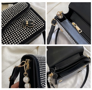 Close-up of black crossbody bag with silver studs, pearl chain and internal compartments