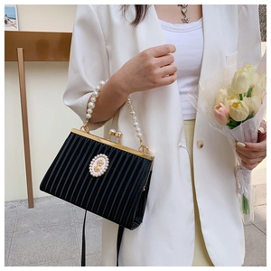Détail d'un sac à main plissé noir rétro avec poignée en perles et emblème ovale chic