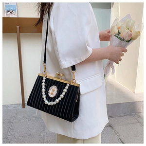 Détail du sac plissé vintage noir avec anse en perles et emblème doré élégant