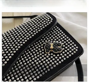 Detail shot of black leather square bag with silver studs and bear metal clasp