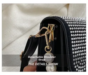 Detail of silver rivets on black shoulder bag with pearl pendant and detachable strap