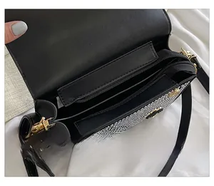 Detail view of the black sequined handbag interior with three compartments and pearl charm