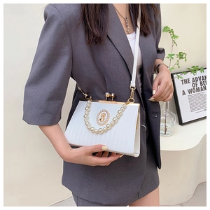 Detail of white textured handbag with pearl handle and vintage cameo relief design