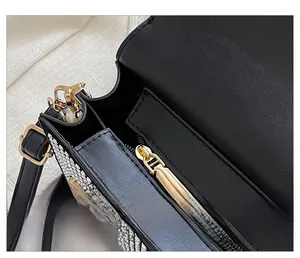 Detail of smooth gold zipper and rhinestone embellishments on a black leather crossbody bag