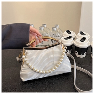 Detail of white shell texture handbag featuring pearl handle and glossy waved finish
