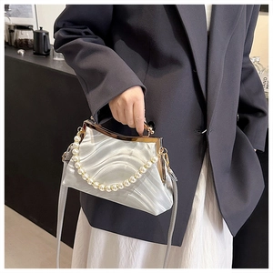 Detail of silver pleated shell bag featuring pearl handle and vintage metal clasp closure