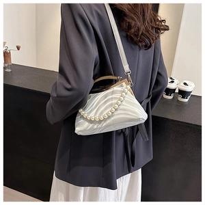 Detailed view of white shell texture clutch bag with pearl strap and gold metal hardware