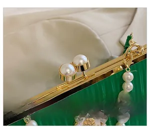 Détail du sac à main plissé vert avec garnitures dorées et fermoir à perles chic