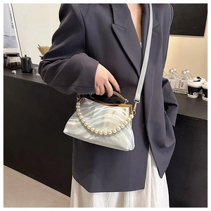 Detail of silver silk shell bag with pearl chain, gold metal frame and long shoulder strap