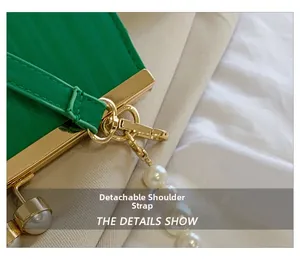 Detail of green pleated satin handbag featuring detachable strap and pearl charm