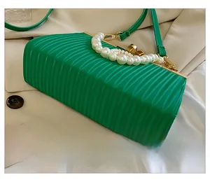 Detail of green pleated clutch bag with gold frame and large pearl handle strap