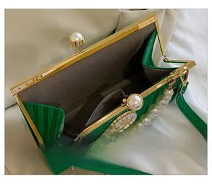 Detail of emerald green evening bag with pearl clasp and herringbone pattern lining