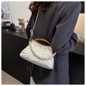 Detail of white wave pattern satin shell bag with pearl handle on grey blazer