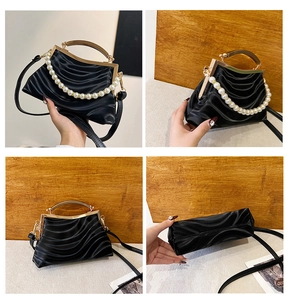 Detail view of black pleated shell bag with vintage metal frame and pearl handle