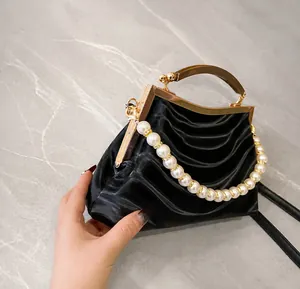 Detail showing the side of a black shell bag with pearl handle and vintage metal frame