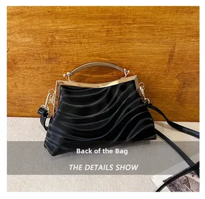 Back view of a black shell bag with wave patterns and golden arched metal handle