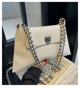 Detailansicht aus weißem gestepptem Kunstleder mit Metallkettenriemen an der Schultertasche