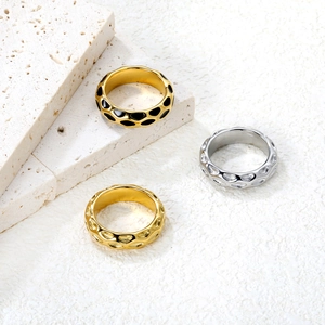 Close-up of irregular textured 18K gold and silver rings with black enamel drip detail