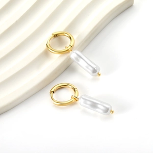 Close-up of gold stainless steel hoop earrings with elegant white cylindrical pearl drops