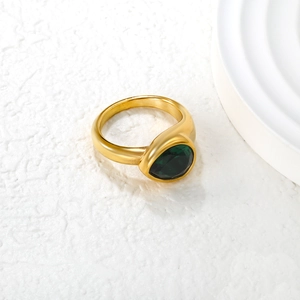 Macro shot of a vintage gold-plated ring featuring a large faceted emerald green zircon