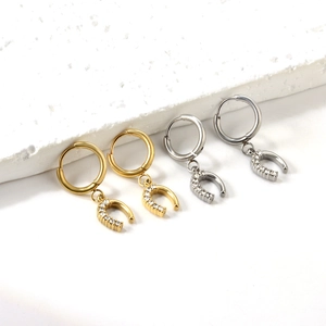 Détail des boucles d'oreilles en U dorées et argentées serties de cristaux de zircon