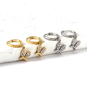 Détail de boucles d'oreilles ailes en or et argent avec incrustation de cristaux blancs